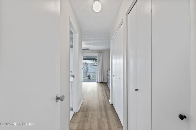 7876 Spanish Oaks Dr, Jacksonville, FL 32221 - hallway featuring a textured ceiling, light wood-style floors, and baseboards