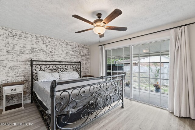 7876 Spanish Oaks Dr, Jacksonville, FL 32221 - bedroom with a textured ceiling, wood finished floors, access to exterior, ceiling fan, and brick wall