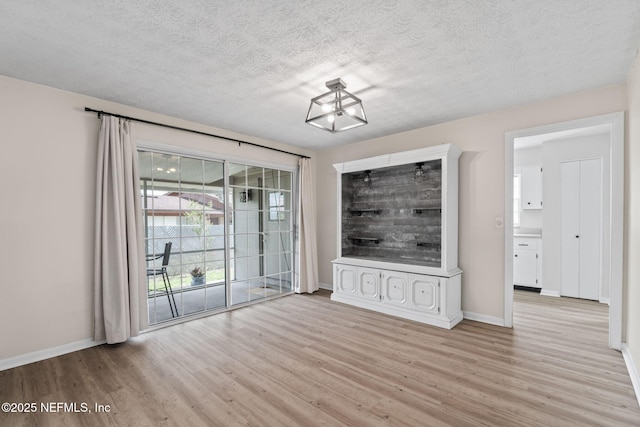 7876 Spanish Oaks Dr, Jacksonville, FL 32221 - unfurnished living room with light wood-style flooring, baseboards, and a textured ceiling