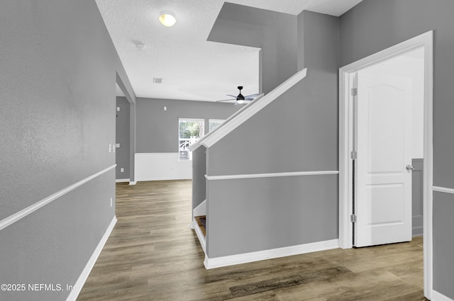 corridor featuring visible vents, baseboards, and wood finished floors