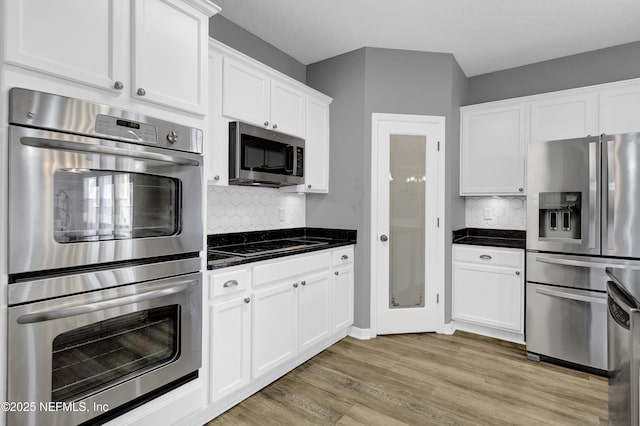 kitchen with stainless steel appliances, light wood-style floors, white cabinets, and decorative backsplash