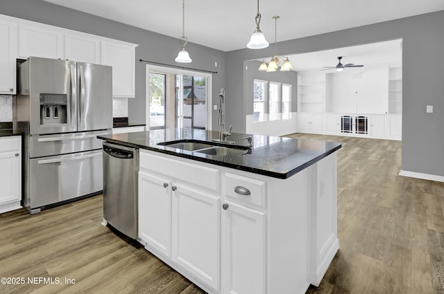 kitchen with an island with sink, light wood-style floors, a sink, and appliances with stainless steel finishes