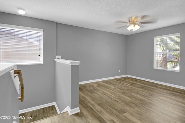 unfurnished room with baseboards, ceiling fan, wood finished floors, and a textured ceiling