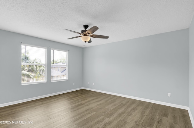 empty room with baseboards, a textured ceiling, wood finished floors, and ceiling fan