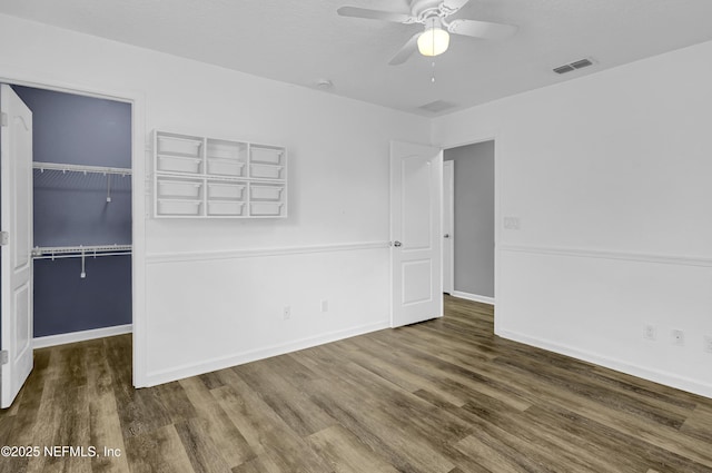 unfurnished bedroom featuring a walk in closet, wood finished floors, a closet, and visible vents