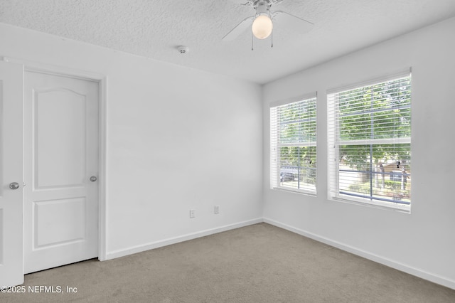 carpeted empty room with baseboards, a ceiling fan, and a textured ceiling
