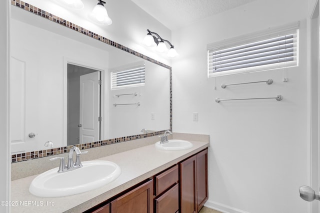 full bath with a textured ceiling, double vanity, and a sink