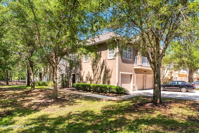 7250 Deerfoot Point Cir Unit 1, Jacksonville, FL 32256 - view of home's exterior with a garage, stucco siding, a lawn, a balcony, and driveway
