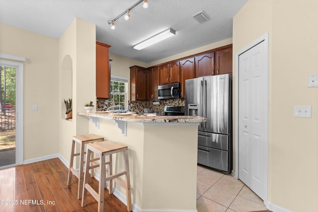 7250 Deerfoot Point Cir Unit 1, Jacksonville, FL 32256 - kitchen with a kitchen breakfast bar, tasteful backsplash, a peninsula, visible vents, and appliances with stainless steel finishes