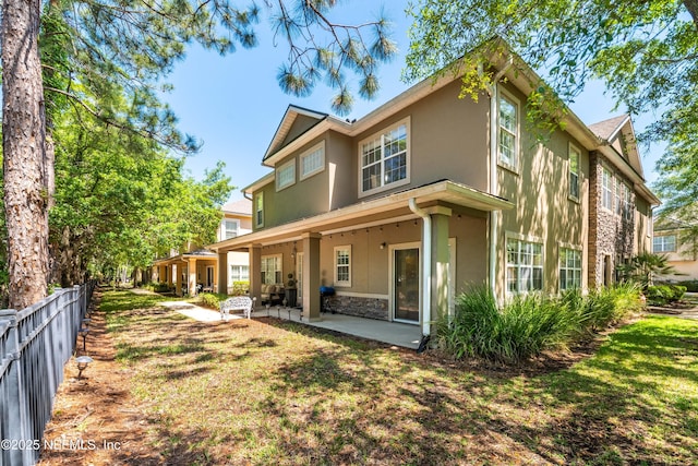 7250 Deerfoot Point Cir Unit 1, Jacksonville, FL 32256 - back of property with a patio, fence, stucco siding, and stone siding