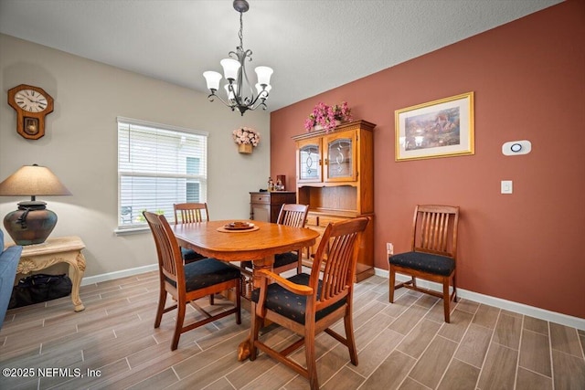 dining space featuring wood finish floors, a notable chandelier, and baseboards