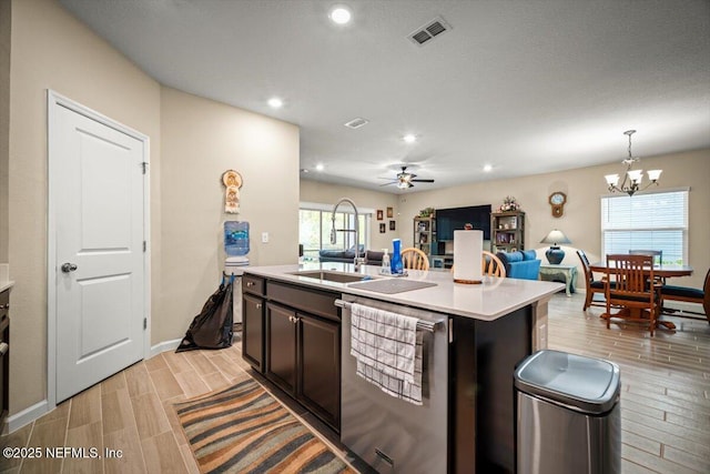 kitchen featuring a sink, dishwasher, light countertops, open floor plan, and wood tiled floor