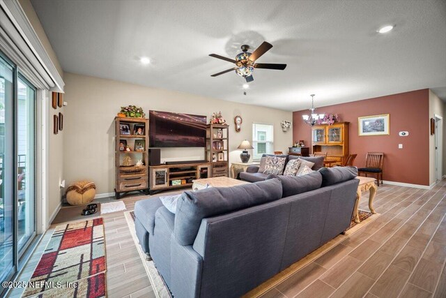 living area featuring recessed lighting, baseboards, wood finished floors, and ceiling fan with notable chandelier