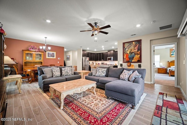 living area with recessed lighting, ceiling fan with notable chandelier, light wood-type flooring, and visible vents
