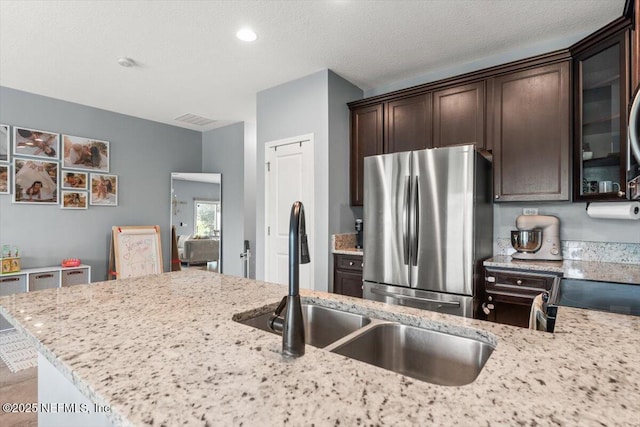 1580 Landau Rd, Jacksonville, FL 32225 - kitchen with freestanding refrigerator, a sink, dark brown cabinets, light stone counters, and glass insert cabinets