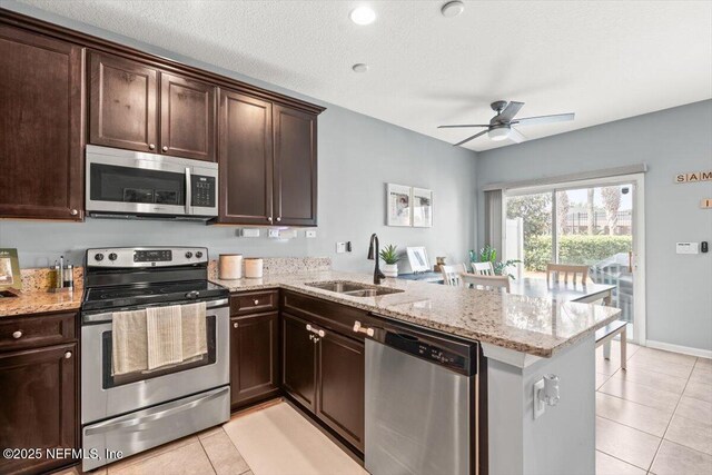 1580 Landau Rd, Jacksonville, FL 32225 - kitchen featuring stainless steel appliances, a sink, a peninsula, light tile patterned flooring, and dark brown cabinets