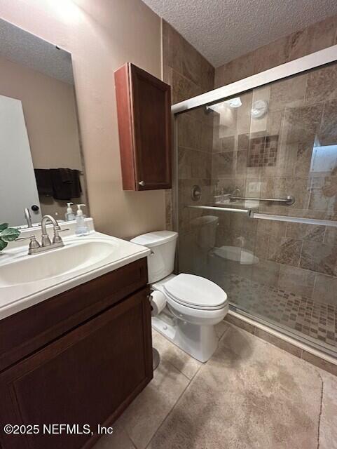 9360 Craven Rd # 607, Jacksonville, FL 32257 - bathroom featuring toilet, a textured ceiling, a shower stall, and vanity
