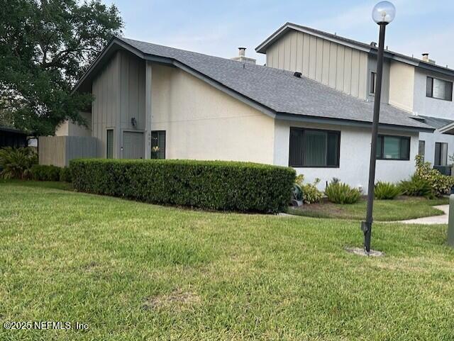9360 Craven Rd # 607, Jacksonville, FL 32257 - view of side of home with stucco siding, roof with shingles, and a yard