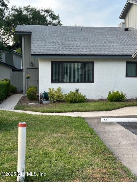 9360 Craven Rd # 607, Jacksonville, FL 32257 - view of front facade featuring uncovered parking, stucco siding, a front yard, and roof with shingles