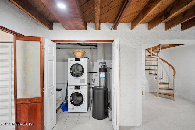laundry room featuring laundry area, stacked washer and dryer, light tile patterned floors, wooden ceiling, and a textured wall