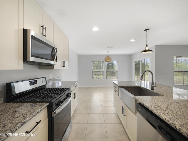 597 Meadow Ridge Dr, Saint Augustine, FL 32092 - kitchen with light stone counters, hanging light fixtures, a sink, stainless steel appliances, and visible vents