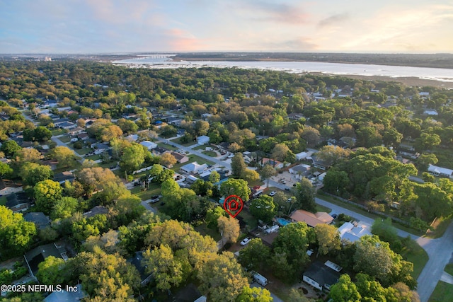 aerial view at dusk featuring a water view and a residential view