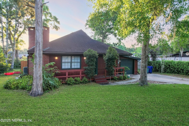 view of front of property featuring a yard, driveway, and a chimney