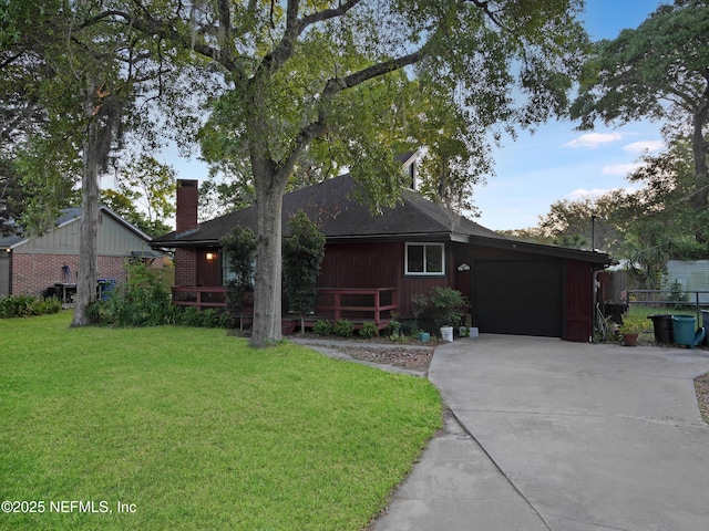ranch-style house featuring a chimney, a front lawn, an attached garage, driveway, and roof with shingles