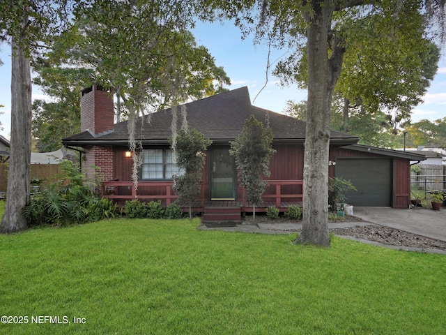 view of front facade with a chimney, fence, an attached garage, driveway, and a front yard