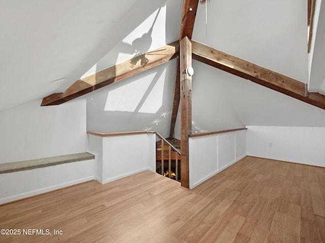 additional living space featuring lofted ceiling with beams, stairs, and wood finished floors