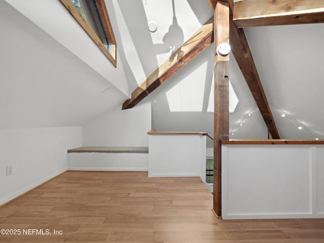 additional living space with beamed ceiling, baseboards, wood finished floors, and high vaulted ceiling