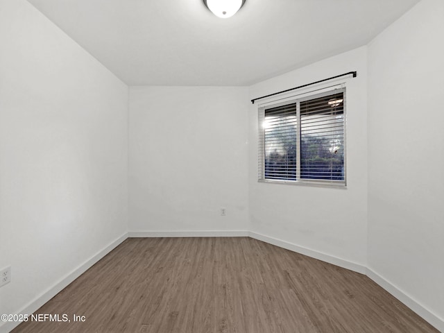 spare room featuring baseboards and wood finished floors
