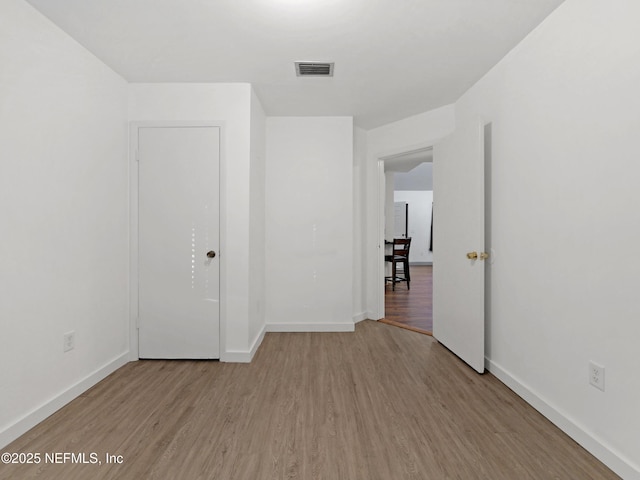 spare room with baseboards, wood finished floors, and visible vents