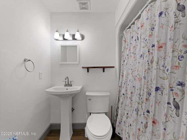 full bath with a sink, toilet, baseboards, visible vents, and wood finished floors