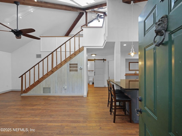 foyer with high vaulted ceiling, a barn door, stairs, ceiling fan, and visible vents