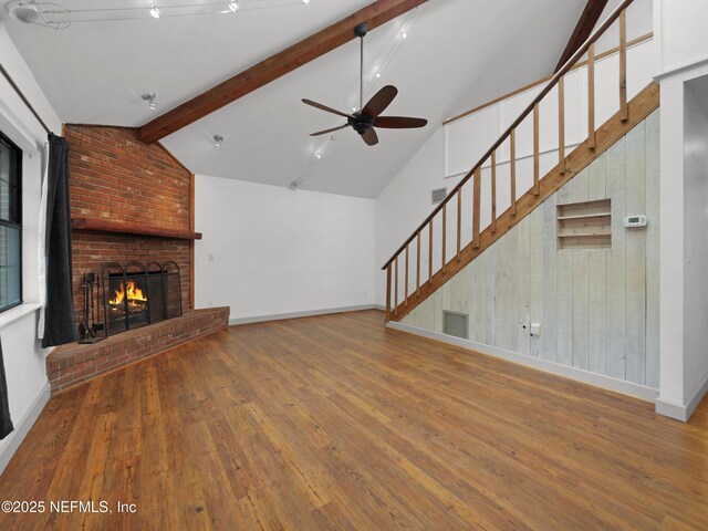 unfurnished living room with visible vents, a ceiling fan, baseboards, lofted ceiling with beams, and hardwood / wood-style flooring