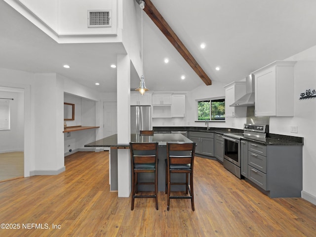 kitchen with wall chimney exhaust hood, dark countertops, appliances with stainless steel finishes, and gray cabinets