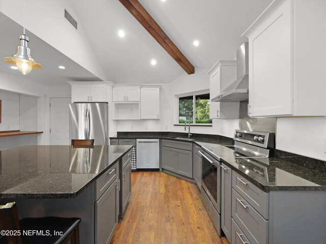 kitchen with open shelves, a sink, lofted ceiling with beams, stainless steel appliances, and wall chimney exhaust hood