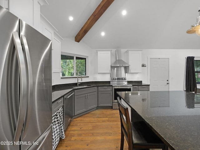 kitchen featuring a sink, recessed lighting, wall chimney range hood, dark wood-type flooring, and appliances with stainless steel finishes