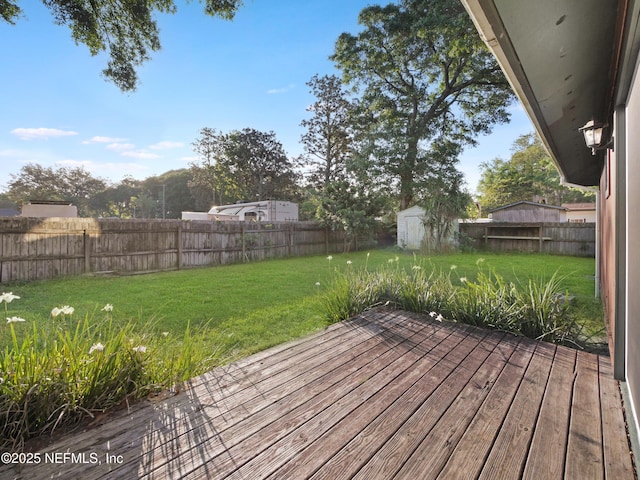 wooden deck with an outdoor structure, a lawn, a shed, and a fenced backyard