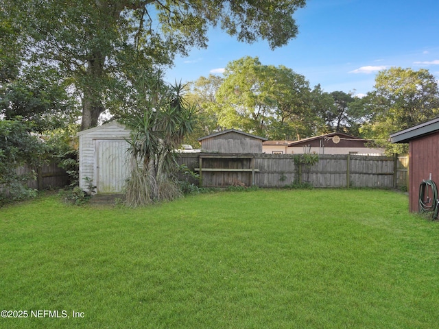 view of yard with a fenced backyard, an outbuilding, and a storage unit