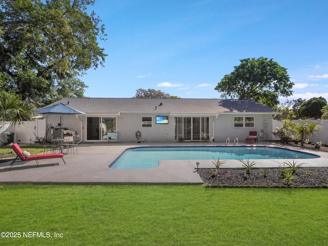 back of property with stucco siding, a yard, a patio, and fence