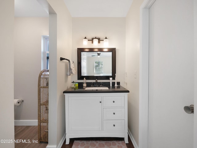 bathroom with baseboards, wood finished floors, vanity, and ceiling fan