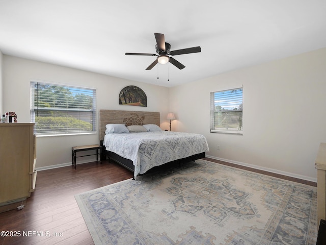 bedroom featuring dark wood-style flooring, a ceiling fan, baseboards, and multiple windows