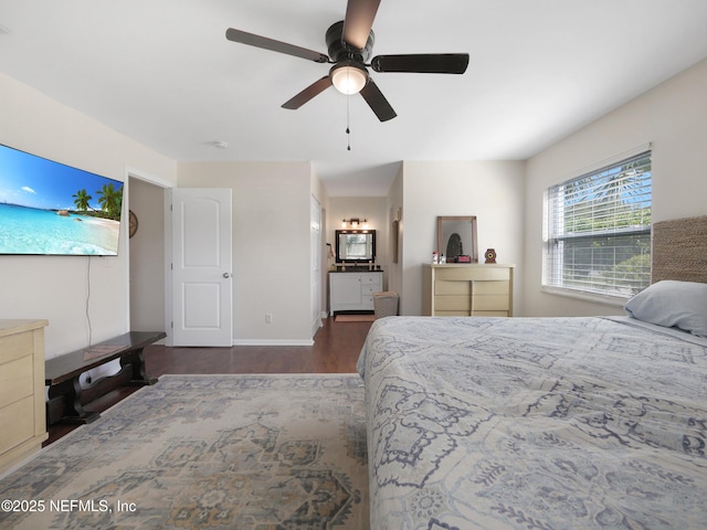 bedroom featuring baseboards, a ceiling fan, wood finished floors, and ensuite bathroom