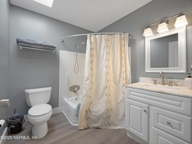 full bathroom with toilet, vaulted ceiling with skylight, shower / tub combo, wood finished floors, and vanity