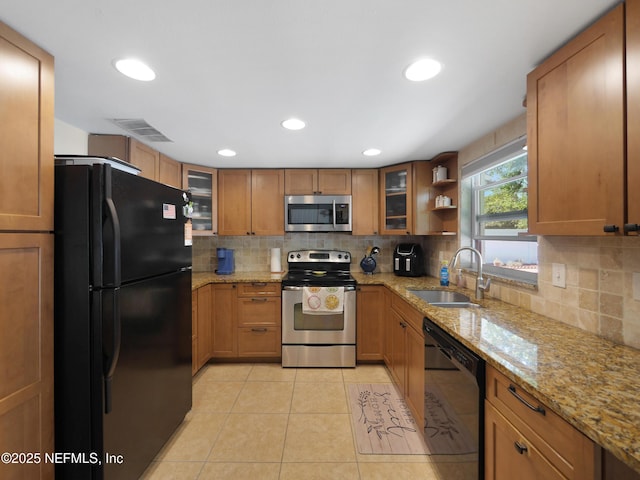 kitchen featuring black appliances, decorative backsplash, a sink, and visible vents