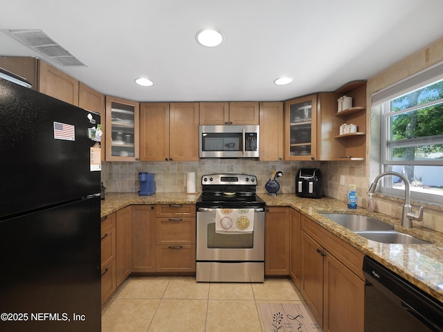 kitchen featuring a sink, black appliances, brown cabinets, backsplash, and visible vents