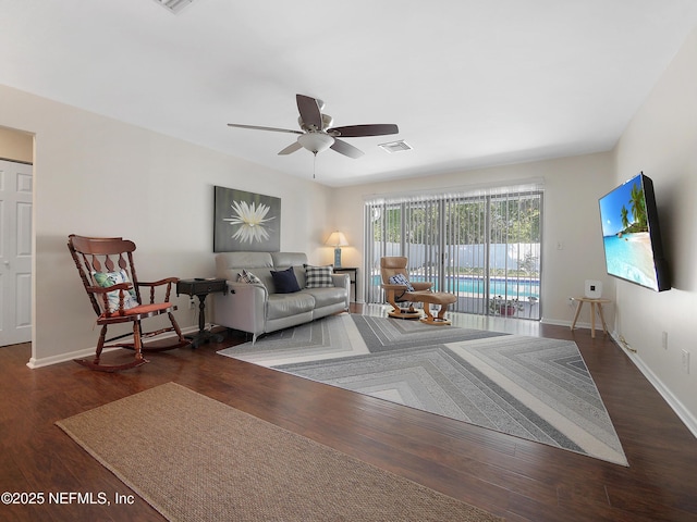 living room featuring wood finished floors, visible vents, baseboards, and ceiling fan
