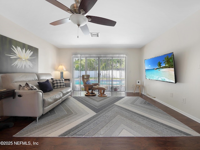 living room featuring wood finished floors, visible vents, baseboards, and ceiling fan